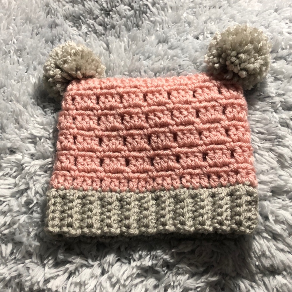 Pink and gray crochet baby hat with pom-poms